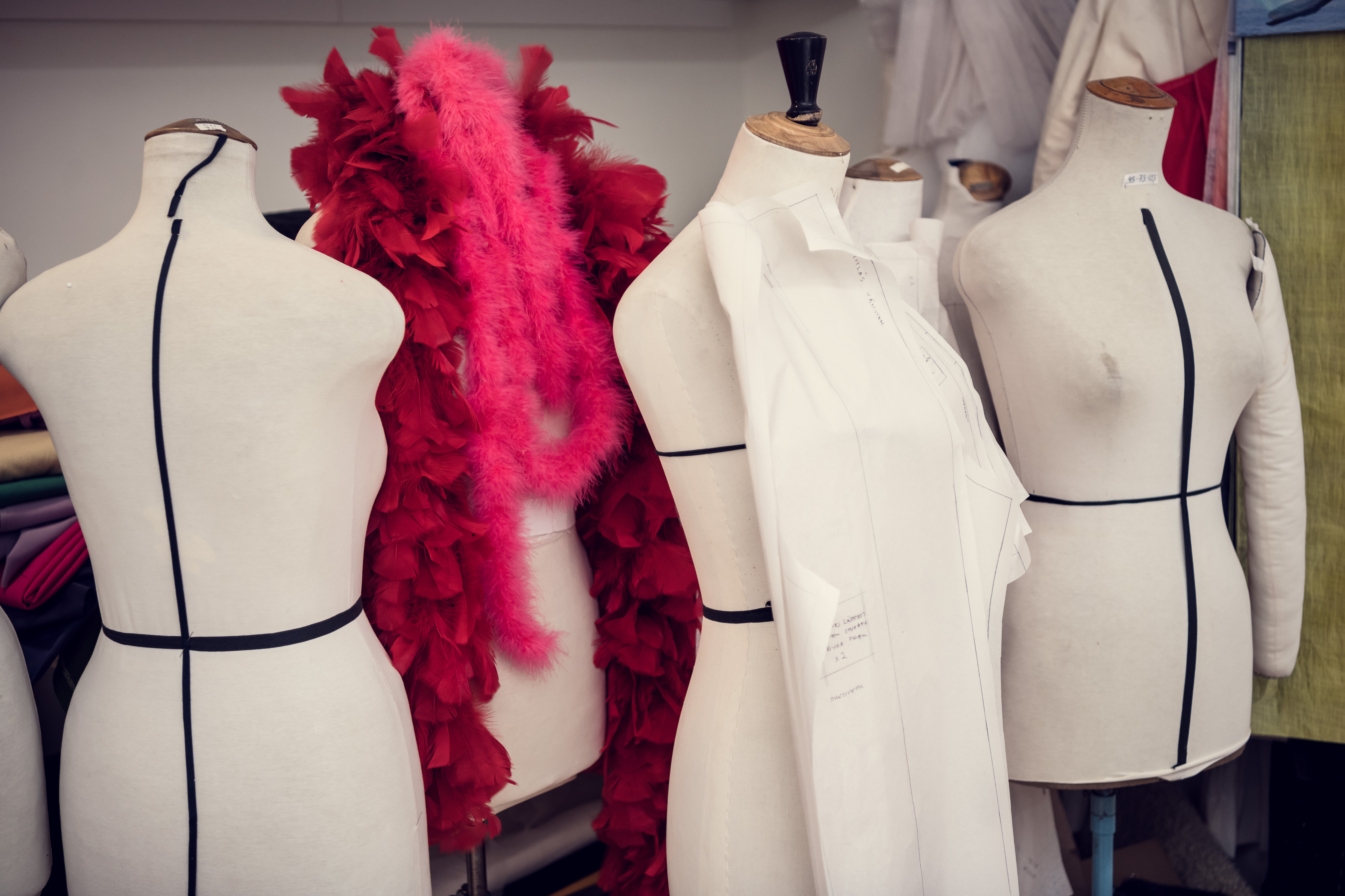 Det står fyra oklädda provdockor bredvid varandra i en grupp varav en har en röd fluffig halsduk runt halsen. 