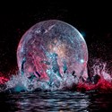 Genomskinlig plastbubbla med en människa innuti som rullar bubblan framåt på en vattenfylld scen.