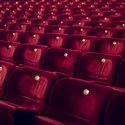 Röda teaterstolar i en tom teatersalong.