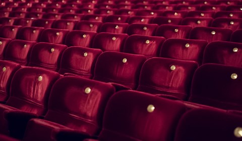 Röda teaterstolar i en tom teatersalong.