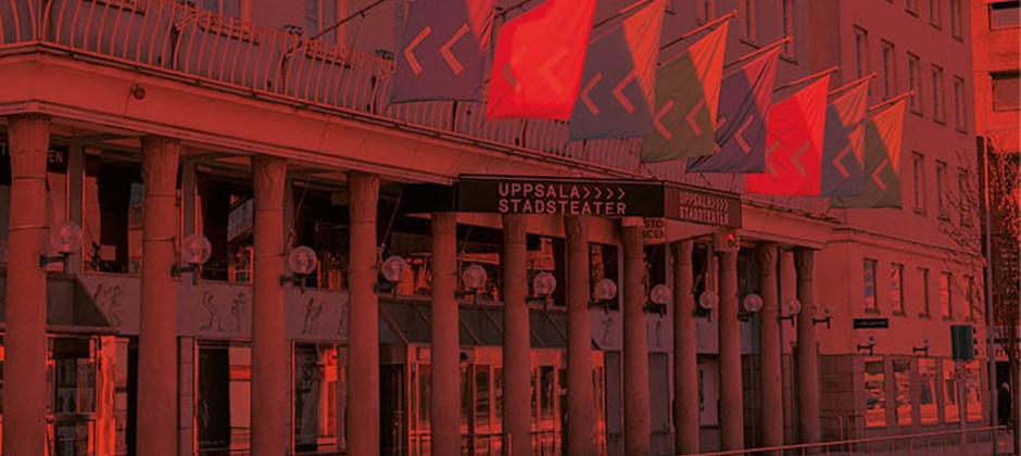 Fasadbild av Uppsala Stadsteater med färgglada flaggor