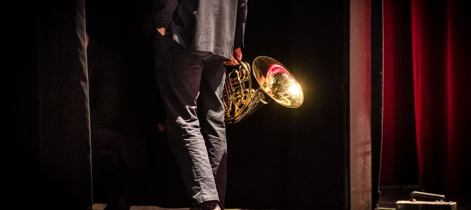 Man går av scenen. Han har en trumpet i handen.  Man går av scenen. Han har en trumpet i handen.