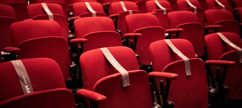 Teatersalong med röda stolsrader, varav flera är täckta med med tejp. Det är en teatersalong med restriktioner för att hindra att människor sitter för nära varandra under pandemin. 