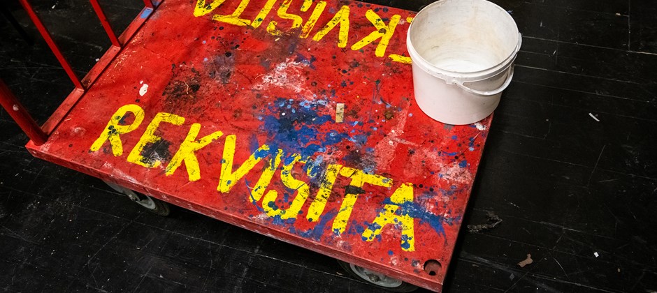 Målad lastvagn i rött med texten Rekvisita i gula stora bokstäver. Målad lastvagn i rött med texten Rekvisita i gula stora bokstäver.